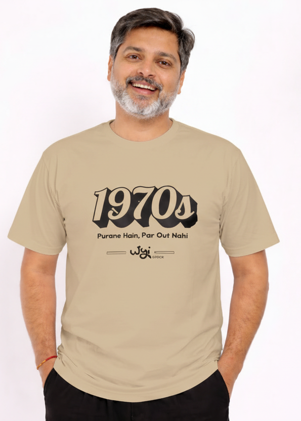 Man wearing a wyi beige t-shirt with '1970s' text and black pants on a white background