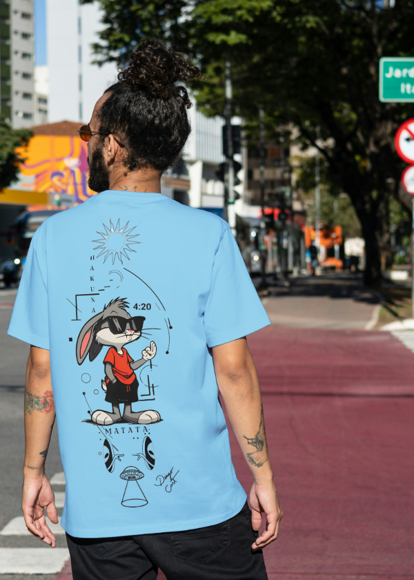 Person wearing a blue t-shirt with a graphic design on a city street.