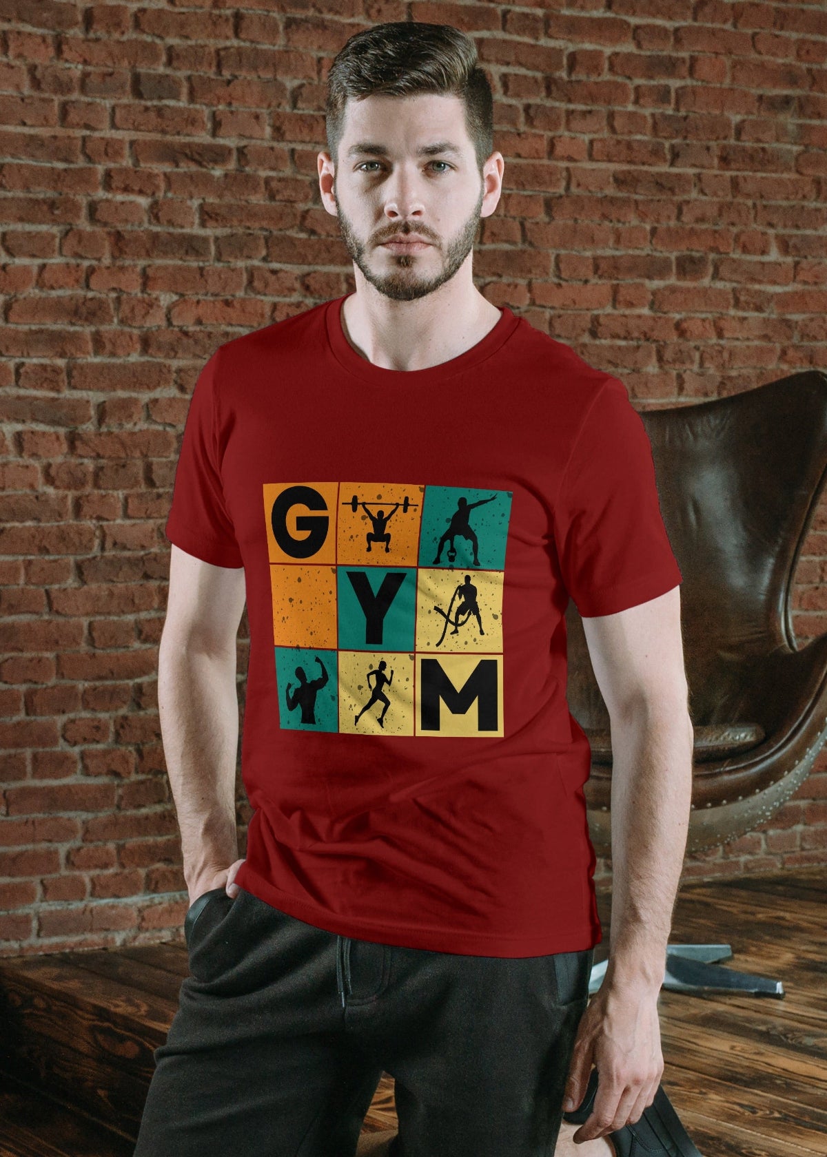 Man wearing a red t-shirt with a colorful 'GYM' graphic design against a brick wall.