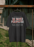 Black t-shirt with text 'The World Perspective' on a hanger against a metal fence.