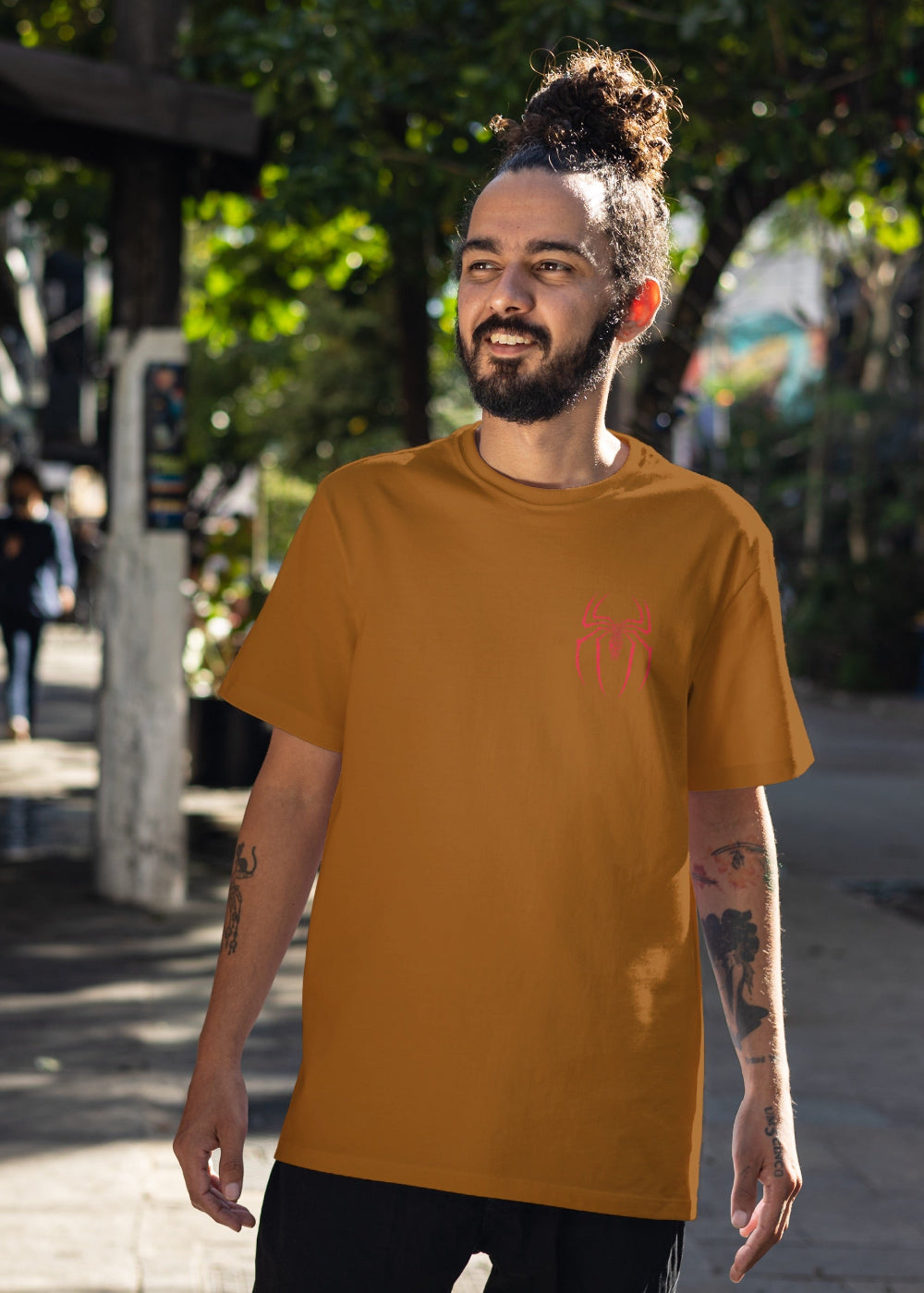 Man wearing a mustard yellow t-shirt with a red logo on a street background