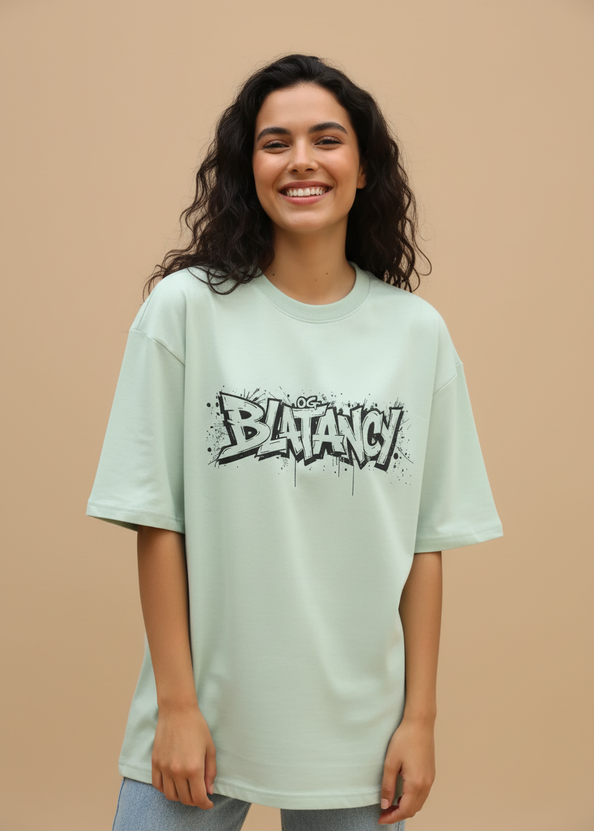 Woman wearing a WYI sage green t-shirt with 'BLATANCY' graphic design on a beige background