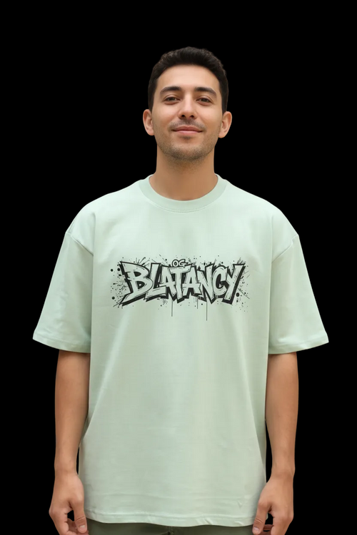 Male wearing a WYI sage green t-shirt with 'BLATANCY' graphic design on a black background
