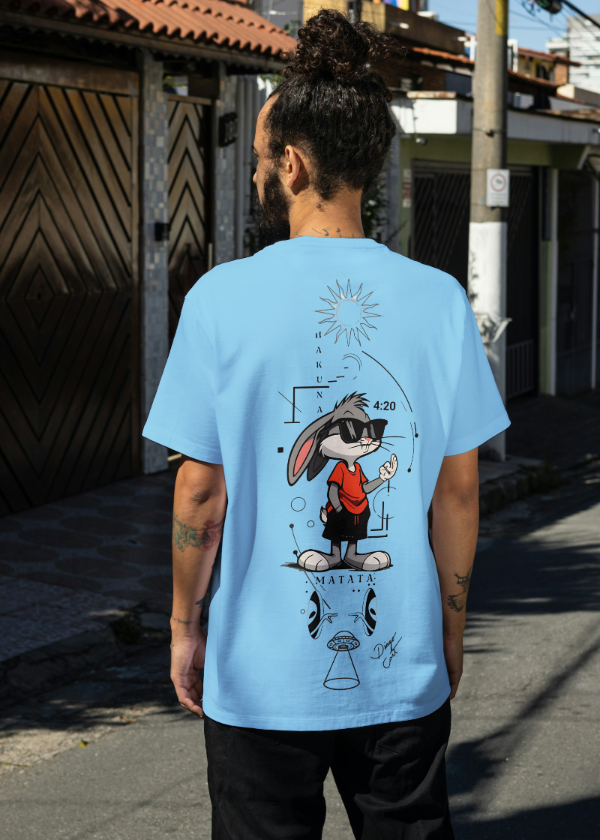 Person wearing a light blue t-shirt with a graphic design on a street.