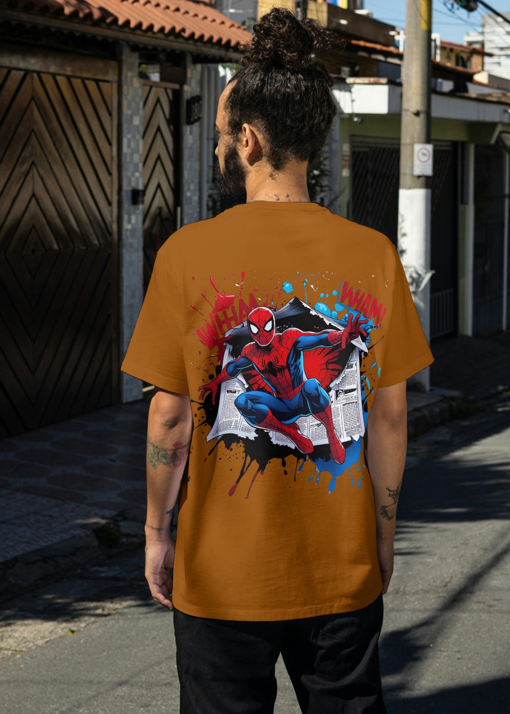 Person wearing a mustard yellow t-shirt with a Spider-Man graphic on a street.