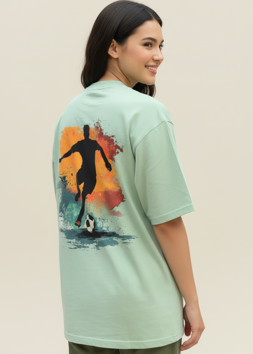 Women wearing a WYI sage green t-shirt with a soccer graphic on the back against a brown background